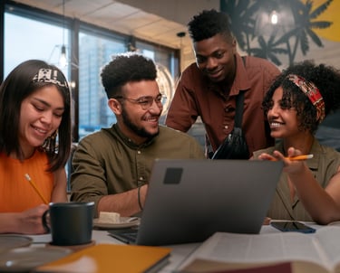 Groupe de jeunes étudiants devant un ordinateurs et des cahiers et livres