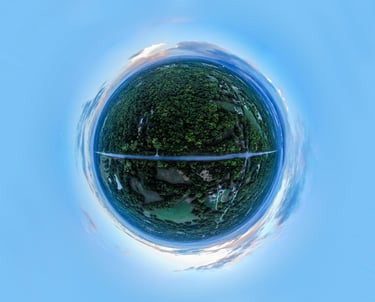 Spherical aerial panorama of a forested landscape with a straight road cutting across a small planet at dusk.