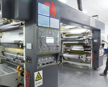 Industrial solventless laminator machine operating in a professional flexible packaging factory facility.