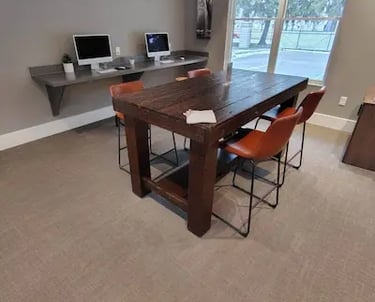 Picture of an office with two computer monitor and a table with four red chairs