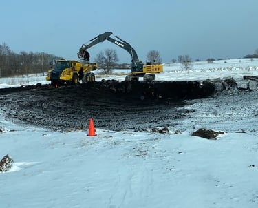 John Deere excavating pond in winter