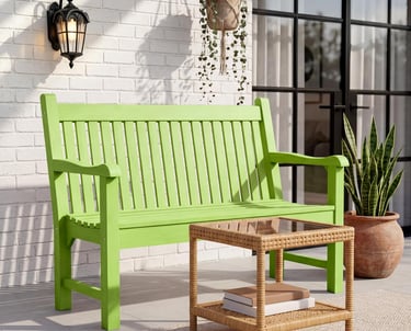 Modern lime green wooden garden bench on a patio with a wicker side table and hanging plant.