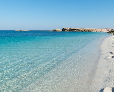 Clear turquoise water and white quartz pebbles at Is Arutas beach in Sardinia under a blue sky.