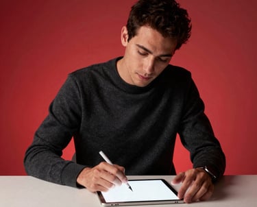 Portrait of a lead creative designer for book covers in a North American / US studio, dressed in black and slate gray, working on a bone white tablet under garnet red ambient light.