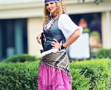 Woman in a pirate costume with a purple skirt and bandana posing outdoors.
