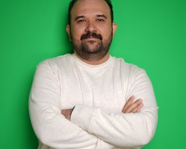 Portrait of a man with a mustache and beard in a white sweatshirt against a green background.