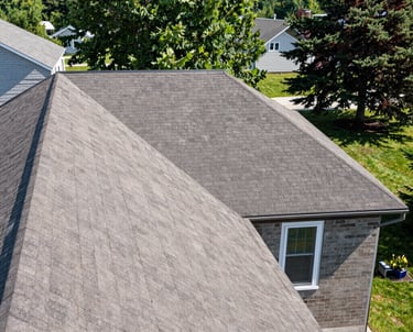 Close-up of a sturdy roof with fresh shingles under a clear blue sky.