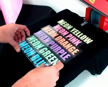 Applying neon heat transfer vinyl labels to a black t-shirt using a professional heat press machine.