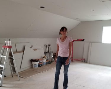 Janestands in a room under construction featuring newly installed drywall and home renovation tools.