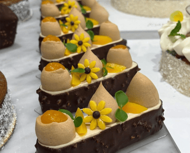 Gourmet chocolate hazelnut mousse cakes with mango filling and yellow flower decorations.