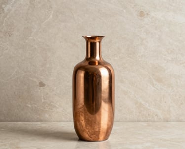 A minimalist interior design shot featuring a copper vase and refined decorative elements on a beige marble surface, representing elegance.