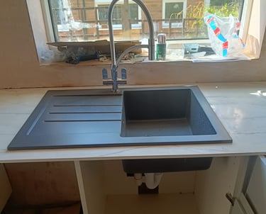 Professional plumber repairing kitchen sink pipework in a residential property