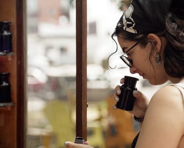 A woman wearing glasses smells different floral and earthy herbs and spices in an apothecary bottle