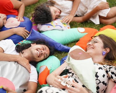 People laugh and play on soft sculptures of body parts.