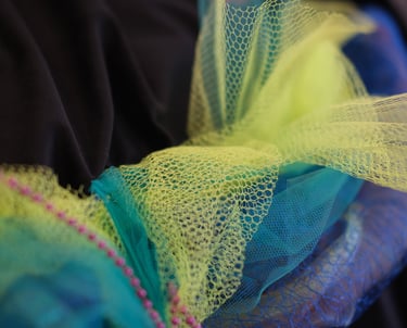 Tulle and net like fabrics twisted with pearls are sewn onto a giant velvet cushion vibrating 