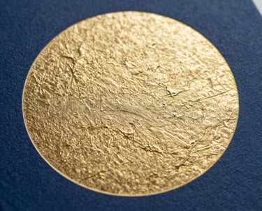 A close-up of a book cover featuring an abstract gold-embossed circle on a deep blue textured surface. Photography, minimalist style.