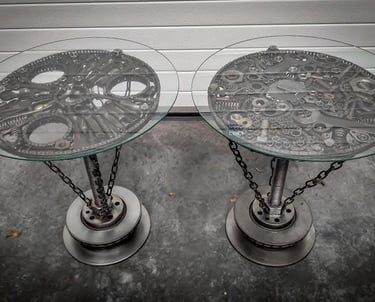 Two steampunk tables crafted from recycled metal tools with round glass tops