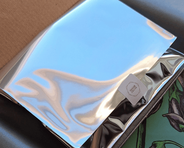 Shiny silver foil package with a Tamar & Talya brand sticker inside a shipping box.