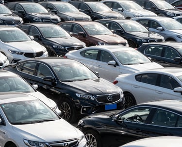 A friendly agent shaking hands with a customer beside a shiny used car.