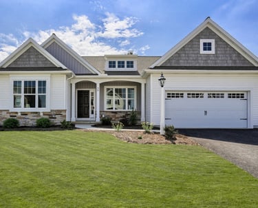 Modern white ranch house with stone accents, a green lawn, and a two-car garage under a blue sky.