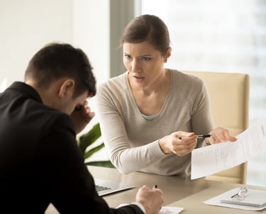 a man and woman sitting at a table with papers