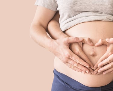 a pregnant woman holding her hands in the shape of a heart