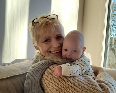 a woman in a sweater and sunglasses is holding a baby
