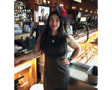 a woman in a dress and hat standing in front of a bar, TWC Financial client