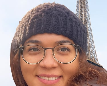 a woman in glasses and a hat on a sunny day