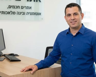 Professional man in blue shirt standing by office desk for AI and automation consulting services.