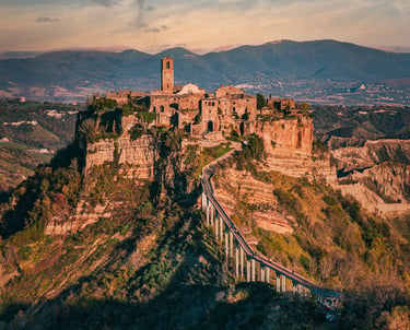 Medieval hilltop village of Civita di Bagnoregio in Italy with its iconic pedestrian bridge at sunset.