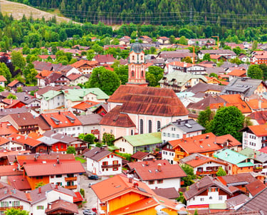Aerial view of Mittenwald, Germany, featuring red-roofed houses and the St. Peter and Paul church in the Bavarian Alps.