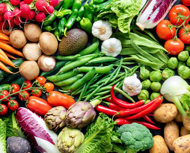 Wide overhead banner of fresh organic vegetables including kale, carrots, tomatoes, and broccoli.