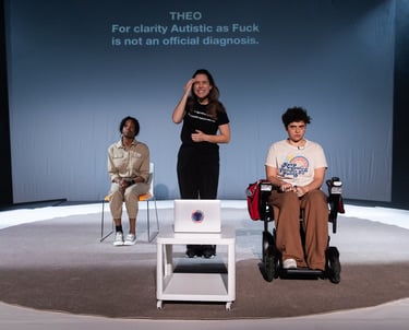 A black woman, a brown electric wheelchair user, and a white woman gathered on a stage