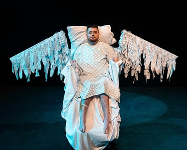 A white electric wheelchair user in a hospital gown with wings made of hospital gown fabric