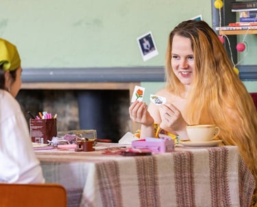 A white person with long blonde hair holding cards out in front of her