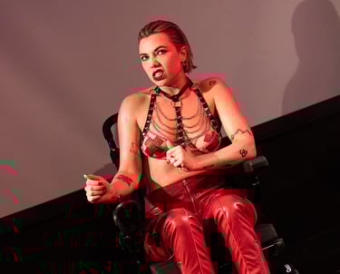 A white electric wheelchair user in red leather trousers and a black leather harness