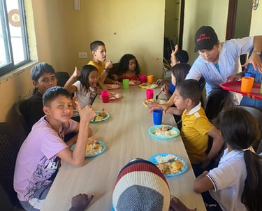 un grupo de niños y adultos sentados a la mesa almorzando