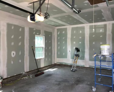 garage in the process of being drywalled with stilts and a scaffold