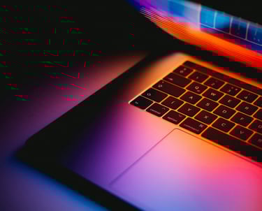 Laptop slightly open with warm colors shining through. Photo by Andras Vas on Unsplash.com