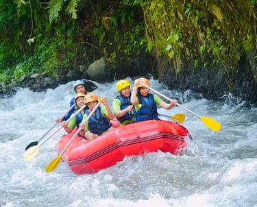 Group of tourists in life jackets white water rafting on a red raft through river rapids.