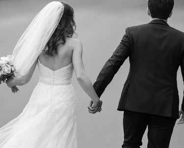 a bride and groom holding hands and walking down a path