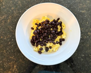 Scrambled eggs topped with black beans in a simple breakfast bowl.