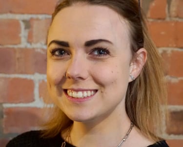 Coach Moll - a woman in her thirties with glasses and a black sweater