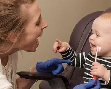 Child holding tooth brush with dentist