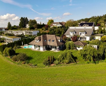 Drohnenaufnahme eines Einfamilienhauses mit Garten, Pool und umliegender Wohngegend
