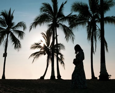 una mujer embarazada en la playa entre palmeras en el atardecer