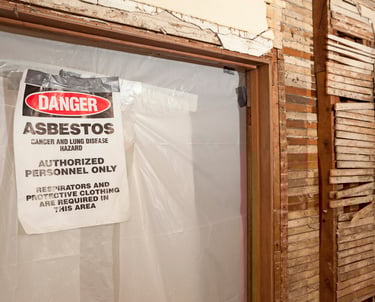 a sign warning of asbestos on a brick wall