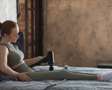 Woman using a massage gun in bed