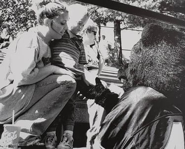 Black and white photo from 1990s of a woman and her child interacting with Topper the Bear